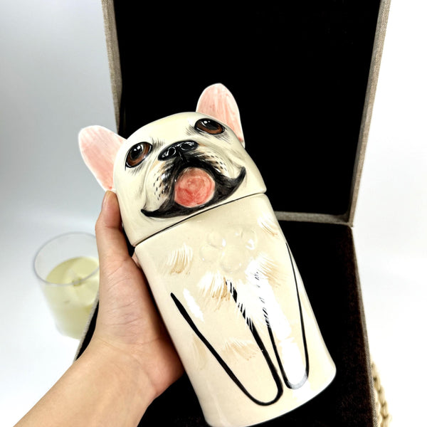 リアルな質感の陶器製骨壺「窯神の祝福」は、かわいらしいフレンチブルドッグのデザインが施された一品です。円筒形のフォルムで、〜するのに適しています。[英文が途中で途切れているため、「円筒形で◯◯しやすい／◯◯に向いている」といったニュアンスまでしか確定できません。用途によって「飾りやすい」「持ち運びしやすい」「収納しやすい」などに訳語が変わります。]